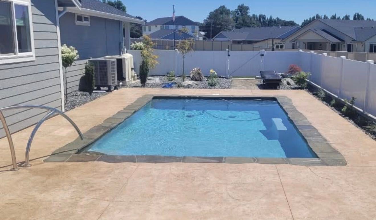 Residential pool with stamped concrete deck and backyard landscaping